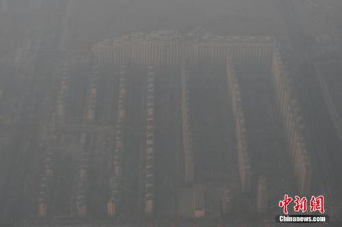 資料圖：2015年12月21日，北京上空航拍空氣重污染，地面建筑若隱若現(xiàn)。12月18日，北京再次發(fā)布紅色預警，12月19日7時至12月22日24時啟動空氣重污染紅色預警措施。實施機動車單雙號行駛、建議中小學幼兒園停課等措施。 <a target='_blank' href='http://www.chinanews.com/'>中新社</a>記者 廖攀 攝