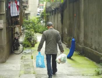 成都某中學外的小區(qū)內，一家長用中午空閑時間給住在這里的孩子買菜做飯。