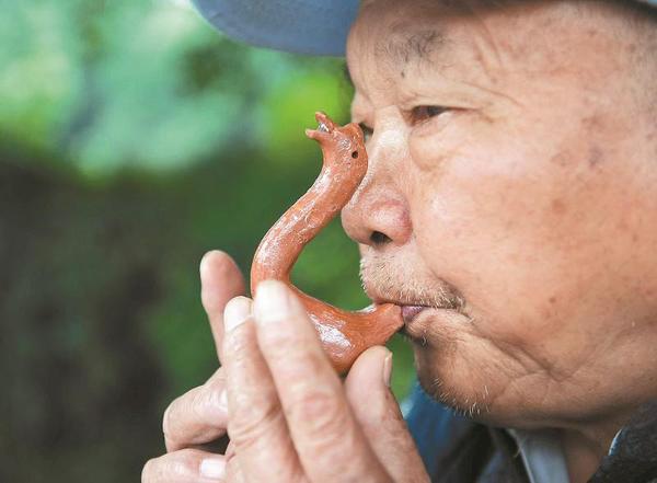 萬富冊老人為過往市民吹奏泥鵝子。