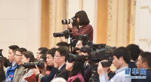 3月7日，一名女記者在十二屆全國人大五次會議江蘇代表團全體會議上采訪拍攝。在兩會會場內(nèi)外，女代表、女委員、女工作人員、女記者在工作中盡職盡責，展現(xiàn)著自己的風采。 新華社記者陳曄華攝