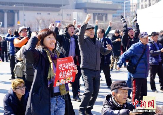 3月10日，在象征著韓國政治中心的首爾光化門廣場，民眾在聽到憲法法院對總統樸槿惠彈劾案的審判結果后歡呼。韓國憲法法院當日作出裁決，宣布彈劾案成立。樸槿惠成為韓國歷史上首位被彈劾罷免的總統。<a target='_blank' href='http://www.chinanews.com/'>中新社</a>記者 吳旭 攝