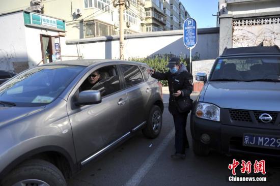 今年元月起，北京全市3000多名路側(cè)停車管理員上崗證更換，新上崗證標有二維碼，市民用手機掃描即可看到管理員的照片、姓名、所在公司、監(jiān)督電話等詳細信息。若冒用或偽造，掃描出來的信息將與實際不符，一旦遇到假收費員，市民有權(quán)拒絕交費。圖為停車場管理員張大姐為車主指揮倒車。<a target='_blank' href='http://www.chinanews.com/' >中新網(wǎng)</a>記者 金碩 攝