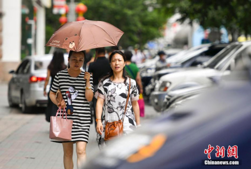 新疆烏魯木齊市街頭，民眾打傘抵擋高溫天氣。