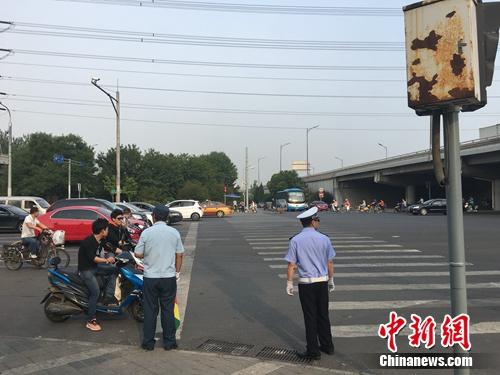 6月21日上午，北京仰山橋下十字路口，執勤人員要求非機動車停在停止線后。湯琪 攝