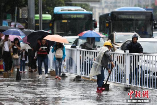 資料圖：行人在雨中出行。 黃芷昕 攝