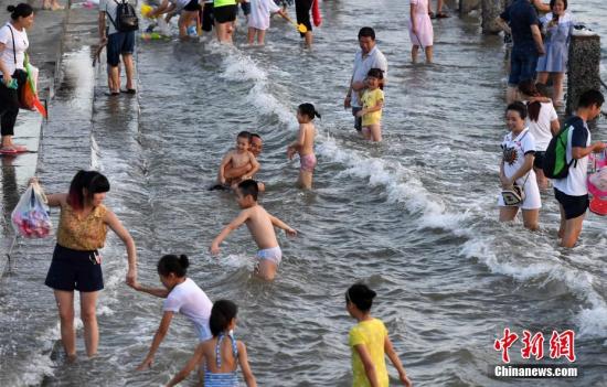 7月4日傍晚，市民們帶著小孩在海邊戲水消暑。連日來，受副熱帶高壓影響廈門地區(qū)持續(xù)高溫。 張斌 攝