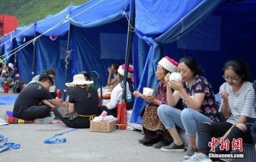 8月10日，四川九寨溝“8.8”地震震源中心附近的臨時安置點，受災(zāi)村民在帳篷邊吃飯。<a target='_blank' href='http://www.chinanews.com/'>中新社</a>記者 劉忠俊 攝