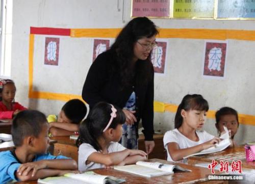 9月22日，在偏遠山區的廣西柳江縣穿山鎮六廟小學，幾間瓦房教室、宿舍，操場上3張乒乓球臺就是學生和老師的一切。48歲的韋鳳玲在給學生們上課，“下雨時，人在上課雨從頭頂落”，韋鳳玲這樣形容學校環境。2014年從老撾完成兩年支教任務的柳江縣第二中學教師韋鳳玲，又到該縣土博鎮、穿山鎮村級小學支教，被稱為支教“專業戶”。朱柳融 攝