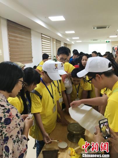 圖為華裔青少年當(dāng)日在廣西自治區(qū)博物館人員的指導(dǎo)下嘗試拓印一面小的銅鼓。鐘建珊 攝