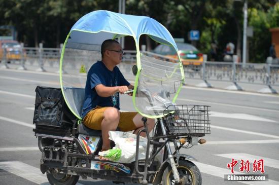 資料圖：男子在電動車上撐起遮陽棚。<a target='_blank' href='http://www.chinanews.com/'>中新社</a>記者 劉文華 攝