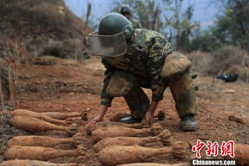 中國人民解放軍南部戰區陸軍云南掃雷大隊在雷場掃雷期間，一名戰士將一枚搜排出來的炮彈放至臨時存放點。　楊萌 攝