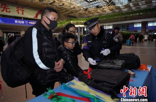 12月28日，北京西站派出所民警為背黑色雙肩包的旅客系上個性小標識，以防在通過安檢或乘車過程中出現錯拿情況。(完) 龐賀雷 攝