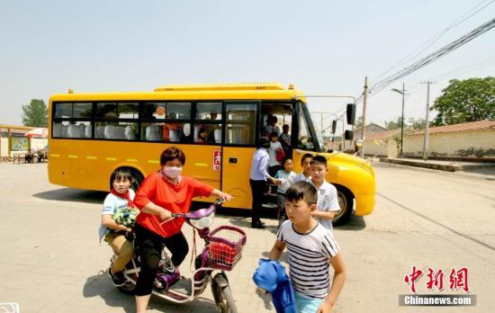 資料圖：學(xué)生家長接送從校車上下來的學(xué)生。 張道正 攝