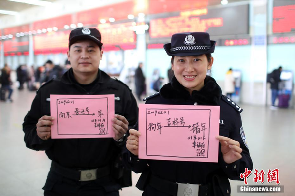 2月1日，隨著春節臨近，南京鐵路公安處南京站派出所的民警在紙上寫下“平安春運，有我們護航”、“天下無賊是我們最大的心愿”、“平安歸途么么噠”等話語，用別樣的方式給旅客們送上溫馨的新年祝福。圖為南京火車站售票大廳內的值班民警和特勤送出溫馨祝福語。中新社記者 泱波 攝