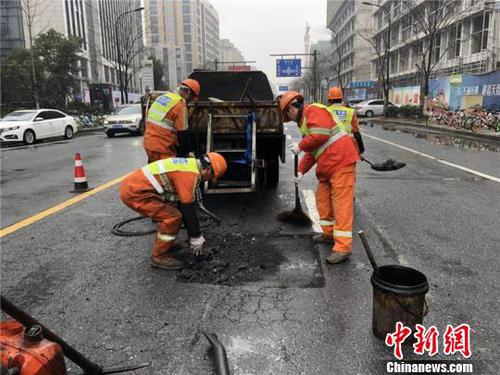 環衛工人修補雨天侵蝕的瀝青路面?！∥骱^城管局提供 攝