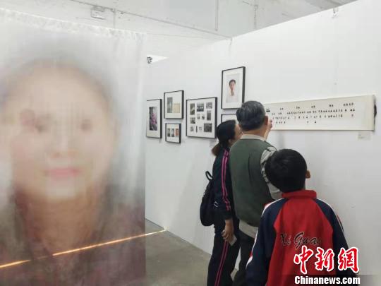 在第19屆中國平遙國際攝影大展柴油機展區(qū)的一角，一張大幅的人像彩畫吸引來往游客駐足拍照。　楊佩佩 攝