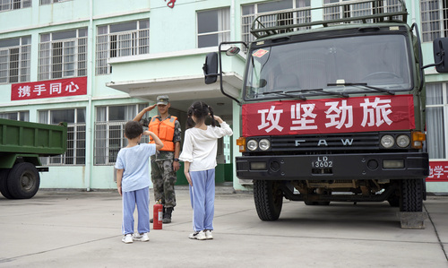 圖為在學(xué)校宿營(yíng)點(diǎn)，小學(xué)生向抗洪官兵官兵敬禮表達(dá)謝意的畫面。（付少旋）